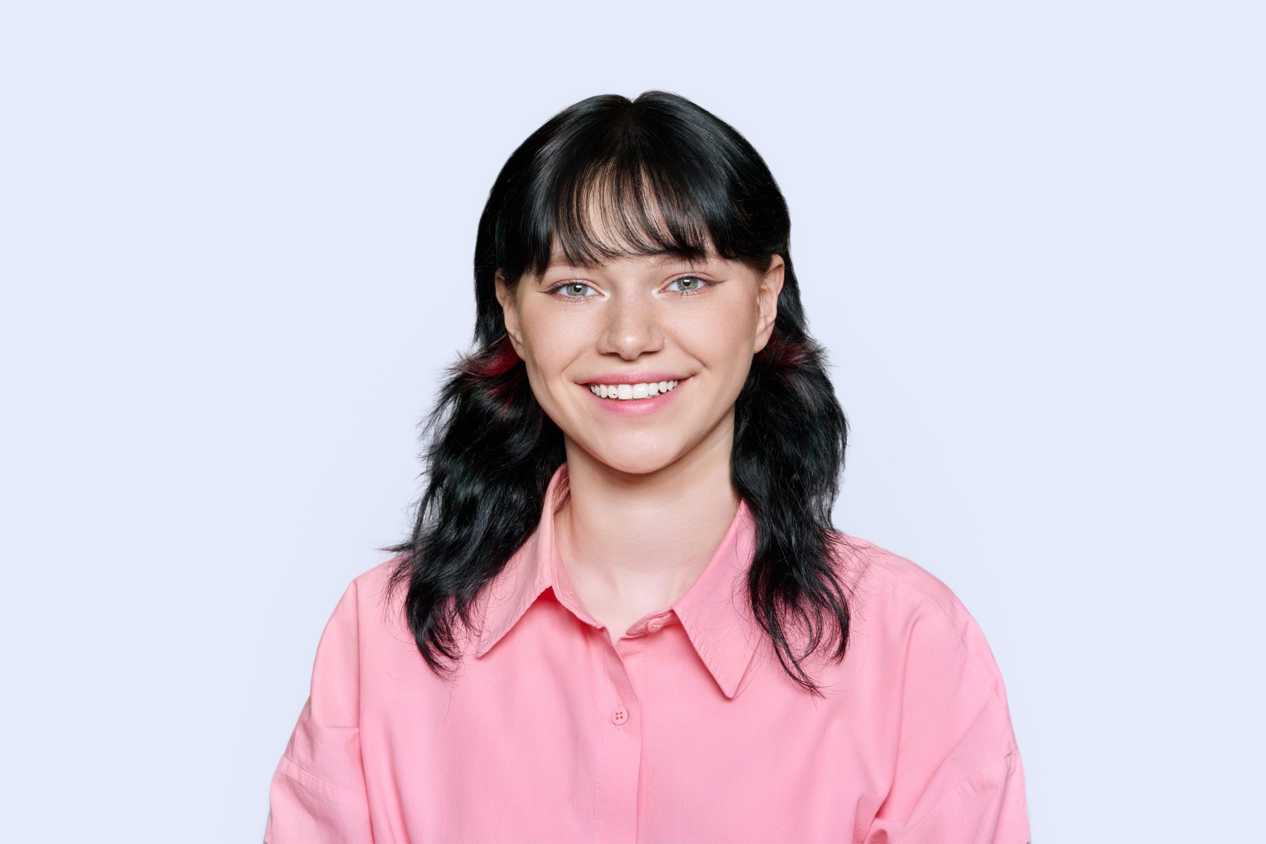 Smiling young female looking at camera on light background Portrait of happy smiling young female looking at camera on light studio background. Attractive girl student 18, 19 years old posing.